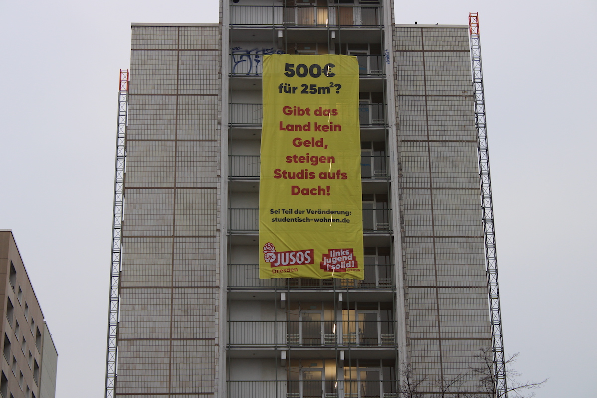 Gerokstraße 38 mit Banner mit der Aufschrift „Wenn das Land nicht zahlt, steigen Studis aufs Dach“ im dunkeln